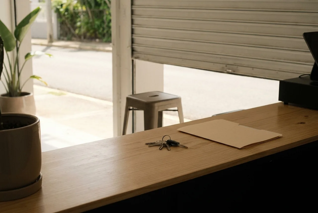 Mostrador de madera de un negocio recién abierto en Puerto Rico, con unas llaves y una carpeta cerrada, y la puerta abriendo hacia la calle